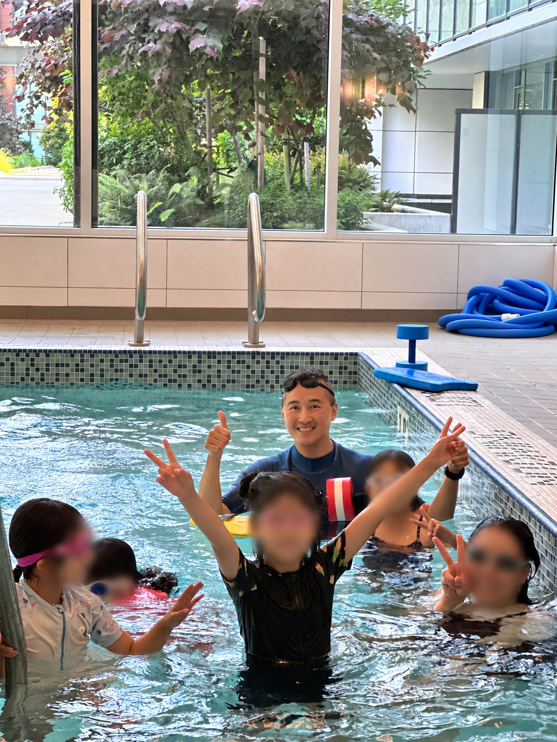 Flying Fish coach teaching a small swimming group; swimmers' faces are blurred